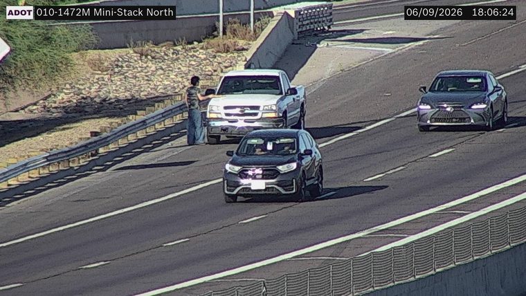 Person standing next to a pickup truck on the right shoulder