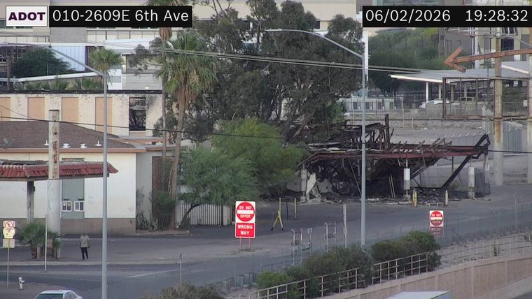 Burned out structure with exposed framing and debris in the roadway
