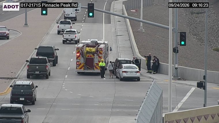 Fire truck and two individuals interacting with a white sedan in the left lane