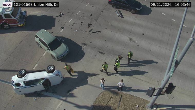 White vehicle overturned in the roadway with debris scattered around
