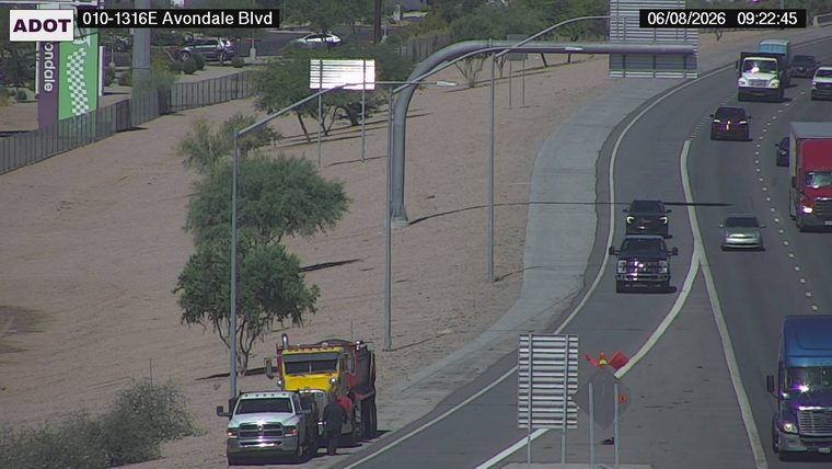 Tow truck and a pickup truck on the right shoulder with a person standing between them