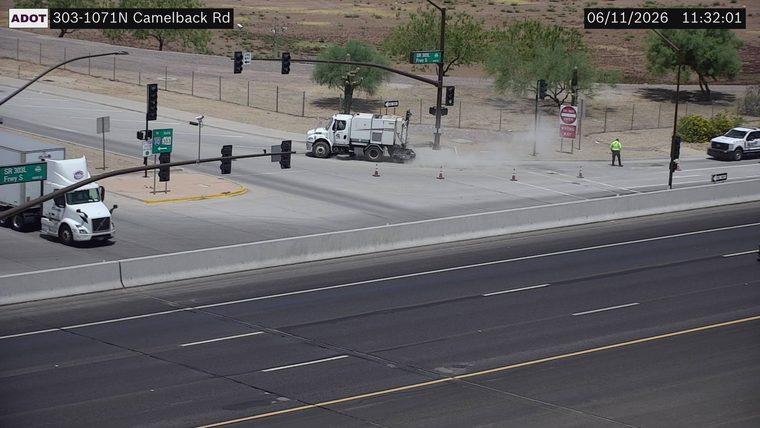 Street sweeper and worker in the roadway with cones