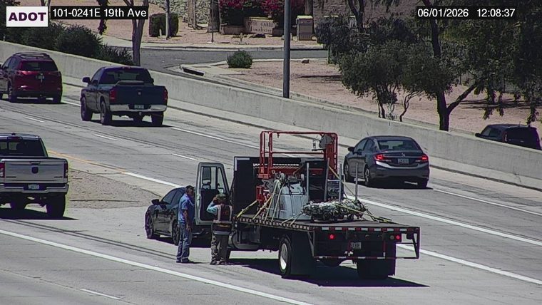 Two workers and a flatbed truck with a lift in the right lane