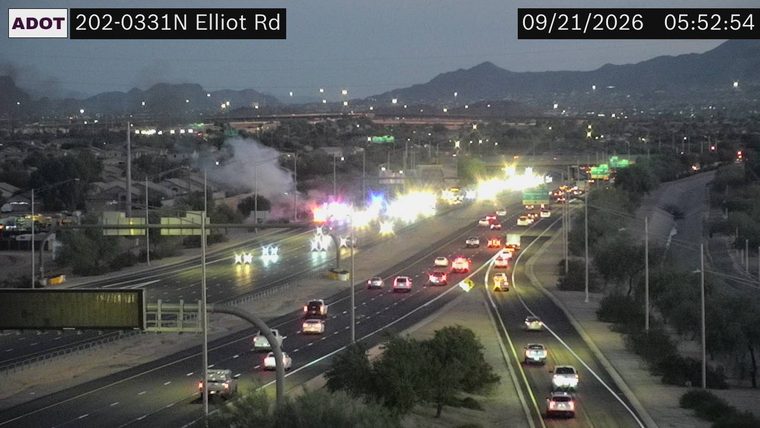 Smoke and multiple emergency vehicles with flashing lights in the left lanes