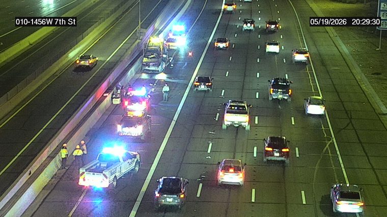 Multiple emergency responder vehicles with flashing lights and personnel on the left shoulder