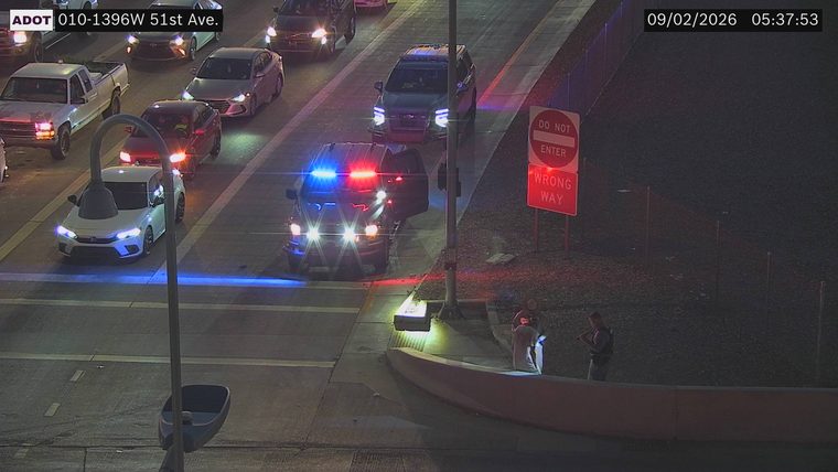 Police SUV with red and blue lights on, door open, in the right lane