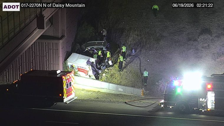 Multiple emergency responders and vehicles at a crash scene involving a U-Haul truck and another vehicle off the roadway