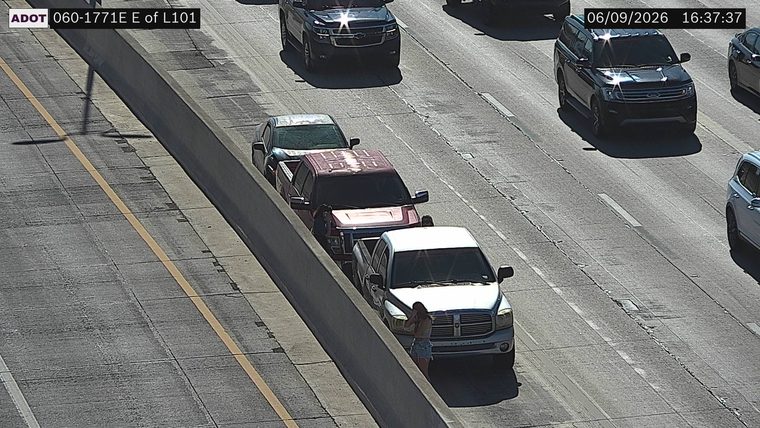 Person standing next to a white pickup truck on the right shoulder