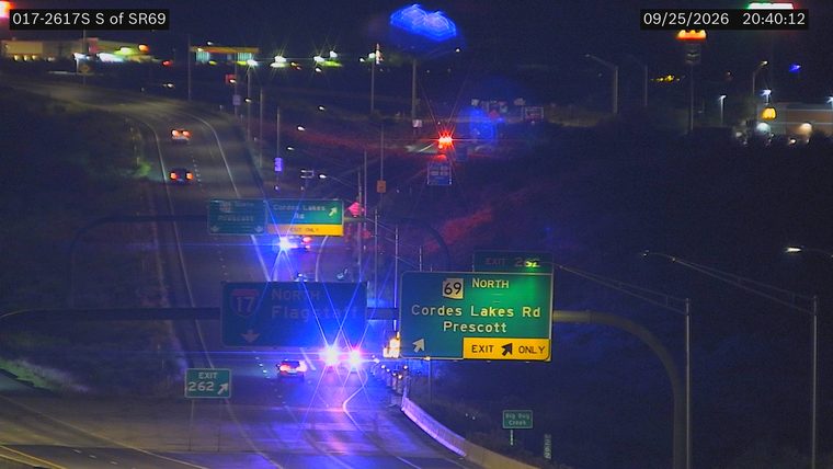 Multiple police cars with red and blue lights active on the right shoulder