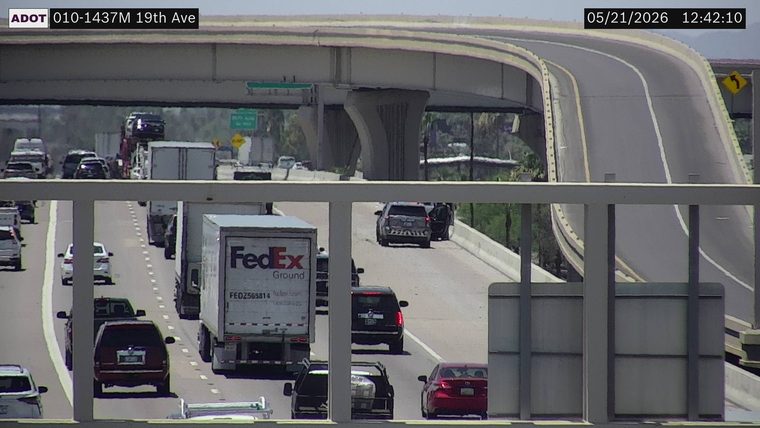 A police vehicle is stopped on the right shoulder of the highway.