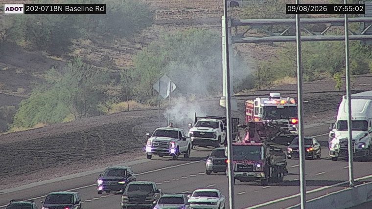 Fire truck with red and blue lights on the right shoulder, smoke visible in the air