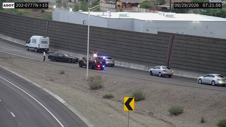 Police car with red and blue lights on the right shoulder next to a damaged black car