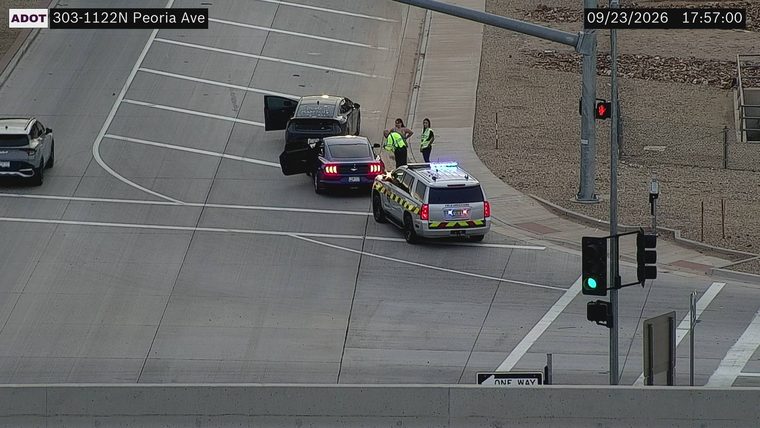 Police SUV with lights on next to two cars with doors open