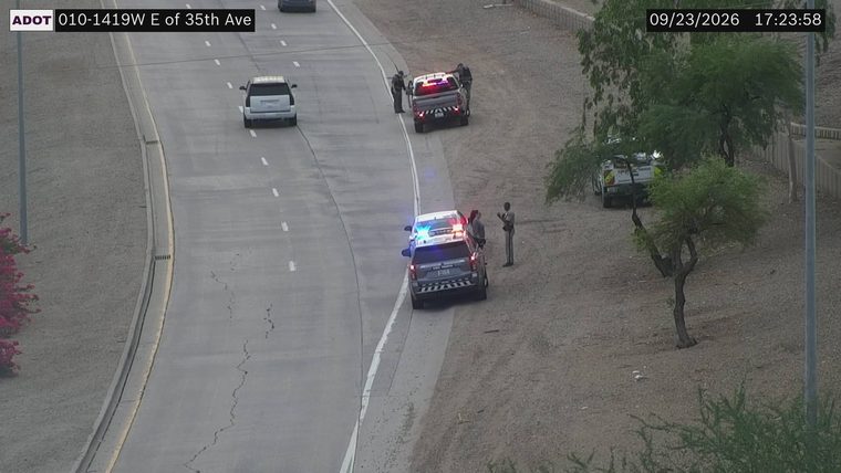 Two police cars and a pickup truck with officers present on the right shoulder