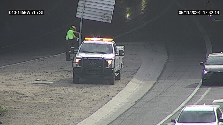 Worker and tow truck with hazard lights on the shoulder