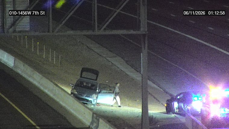 Police car with emergency lights on the shoulder next to a car with an open trunk and door