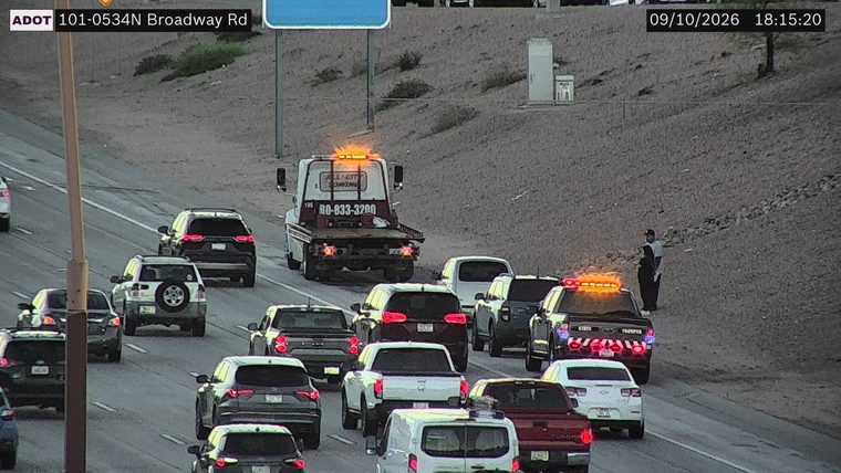 State Trooper vehicle with lights on and a person standing near it on the right shoulder