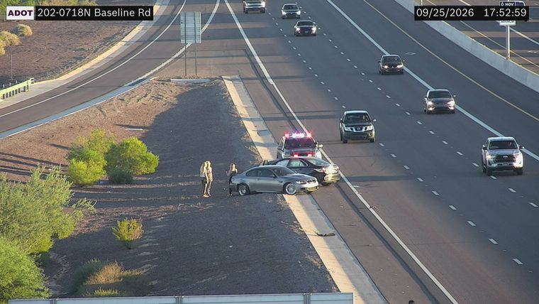 Police car with red and blue lights on the shoulder next to two other vehicles