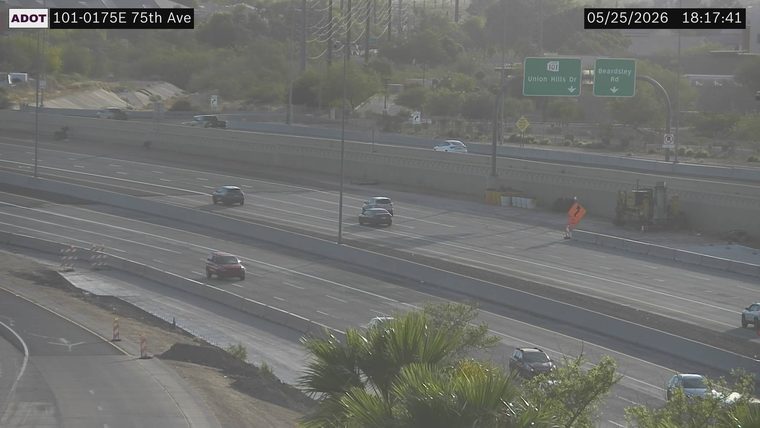 Construction equipment and an orange sign on the right shoulder behind the barrier