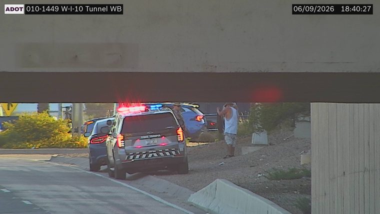State Trooper vehicle with lights on, stopped on the shoulder next to another vehicle and a person