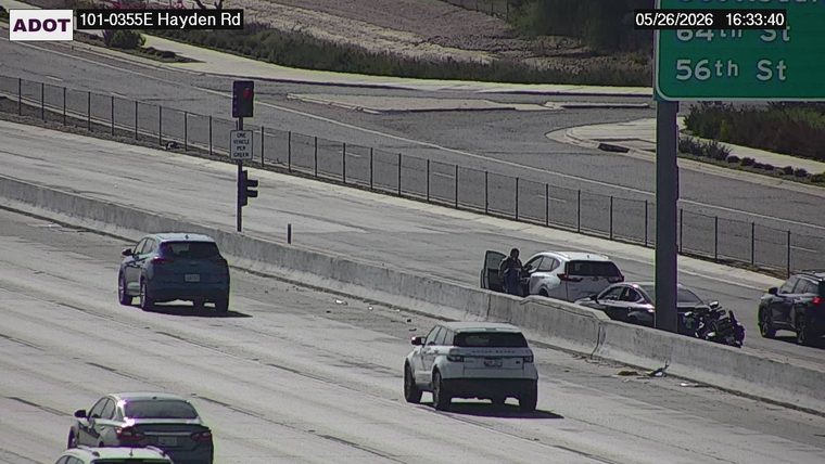 White SUV with driver's door open and a person standing outside, next to a sedan and a motorcycle on the right shoulder