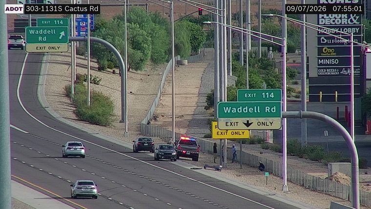 Police car with red and blue lights on the right shoulder, with two other vehicles nearby