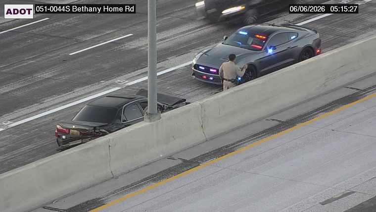 Black sedan with significant rear damage and a police vehicle with lights on next to it