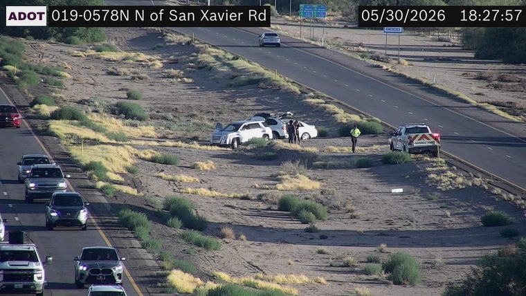 Two vehicles and three people off the roadway, with a utility truck on the shoulder