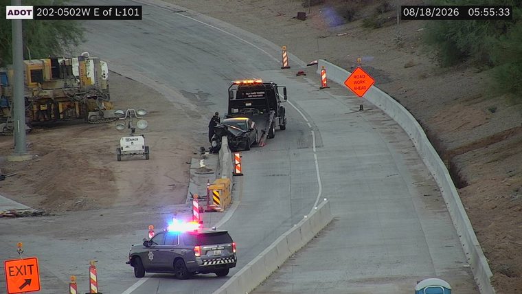 Police car with red and blue lights on the shoulder next to a tow truck and a damaged car