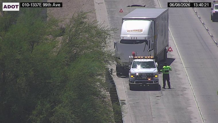 Tow truck and worker assisting a semi-truck on the right shoulder