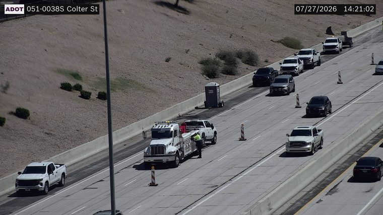Tow truck and a white pickup truck on the right shoulder with a person attending to it