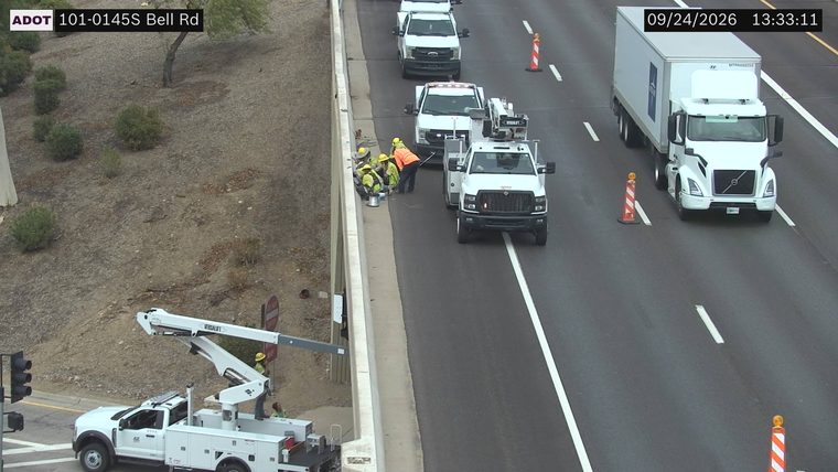 Workers and equipment on the left shoulder and median barrier