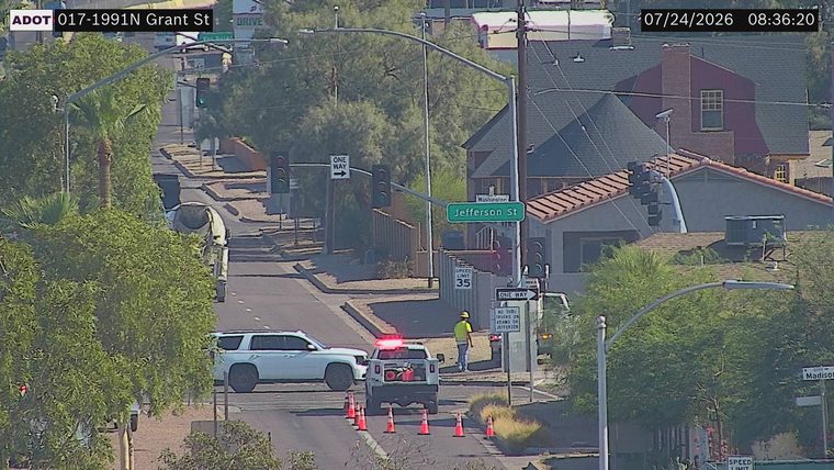 White pickup truck with red flashing lights and traffic cones in the roadway