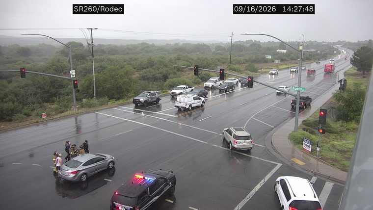 Firefighters and police officers attending to a silver sedan in the intersection