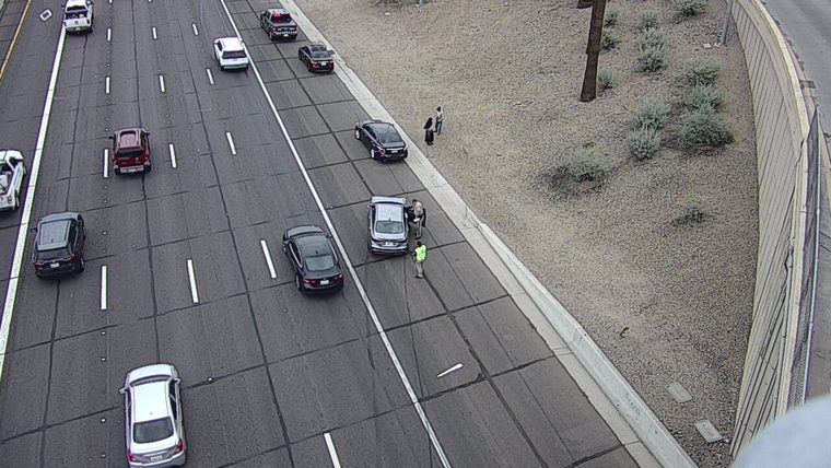 Police officer speaking with occupants of a silver sedan on the right shoulder