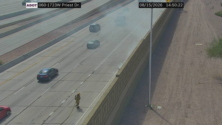 Firefighter with hose on the roadway near smoke