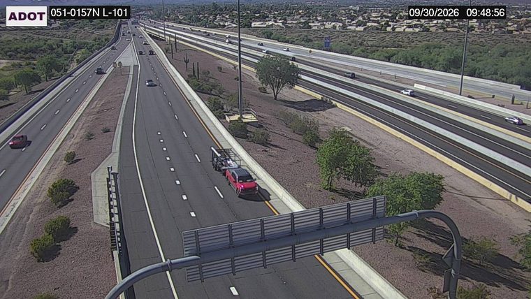 Red pickup truck towing a trailer on the right shoulder