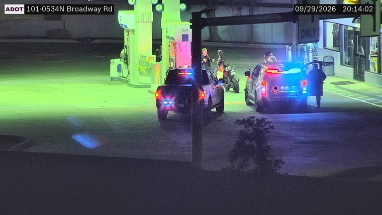 Two police vehicles with emergency lights activated near a gas station