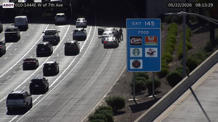 Two vehicles stopped on the right shoulder near the tunnel entrance with an open door and people standing outside
