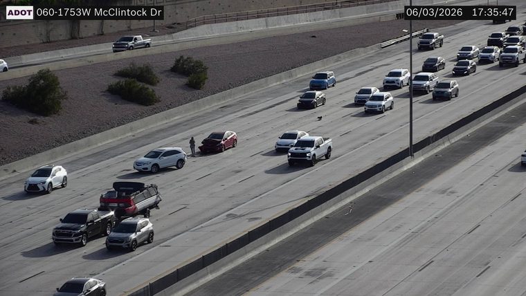 Red sedan with front-end damage and a person standing next to it in the left lane