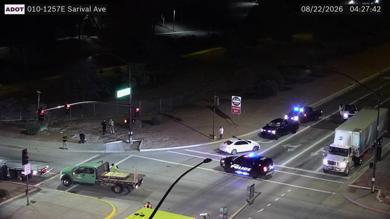 Two police cars with blue lights on and a white car stopped in the intersection