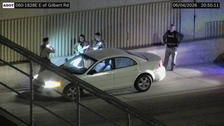 Trooper and two other individuals standing near a white sedan on the right shoulder