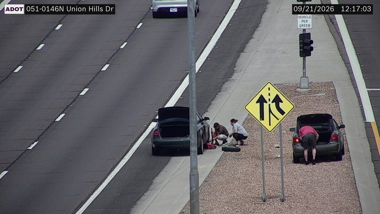 Two people working on a car on the right shoulder