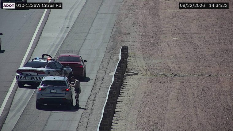 State trooper vehicle with red and blue lights on the shoulder next to a civilian vehicle