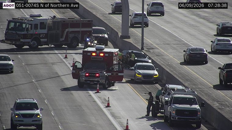 Fire truck and ambulance with emergency personnel attending to a collision in the left lanes