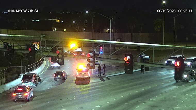 Two police officers standing near a tow truck with flashing lights in the left lane