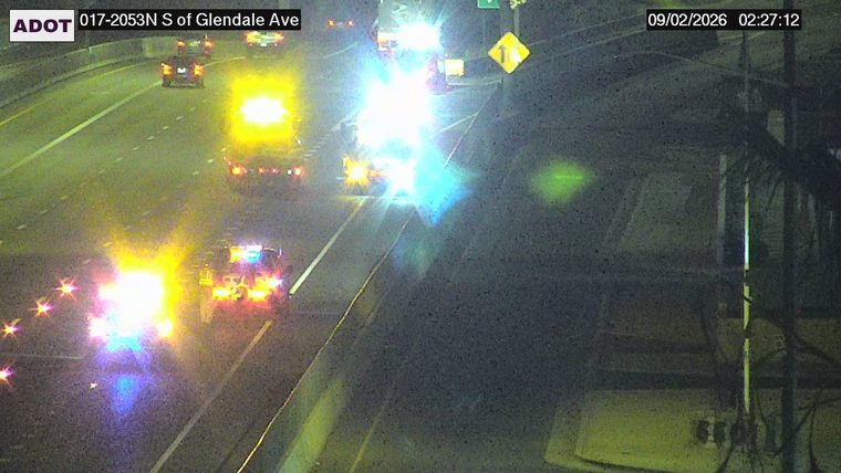 Multiple emergency vehicles with flashing red and blue lights in the left lanes