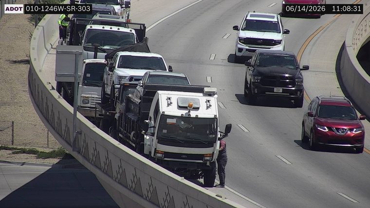 Person standing next to a white truck on the shoulder