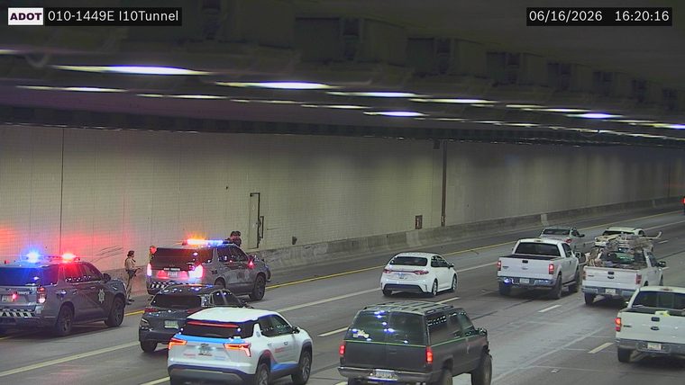 Two police cars with red and blue lights on in the left lane
