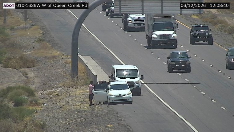Two people standing next to a white car on the shoulder